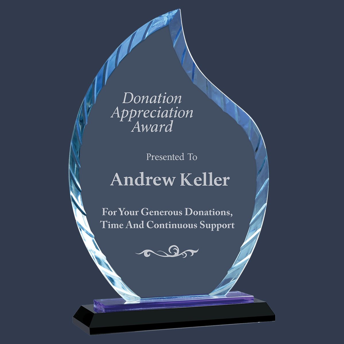 A flame-shaped glass award with a faceted blue edge on a black base, engraved as a donation appreciation award.