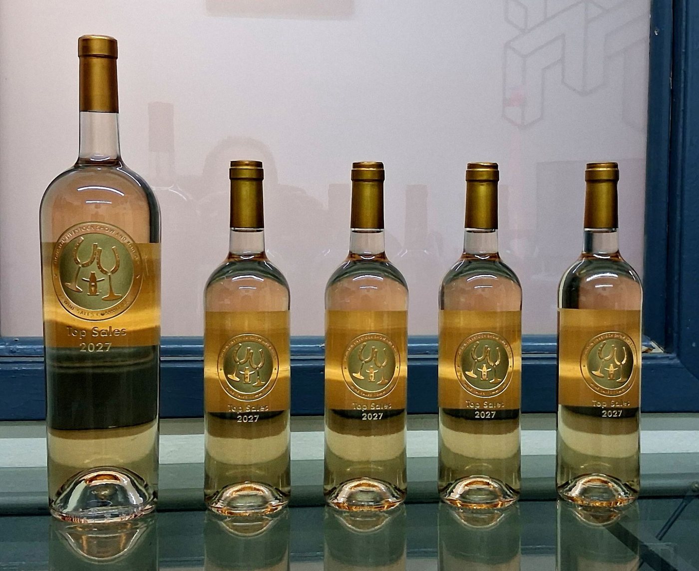 Five gold-labelled Top Sales bottles, a magnum beside four standard bottles, each carrying a Houston Livestock Show and Rodeo wine sales committee medallion.