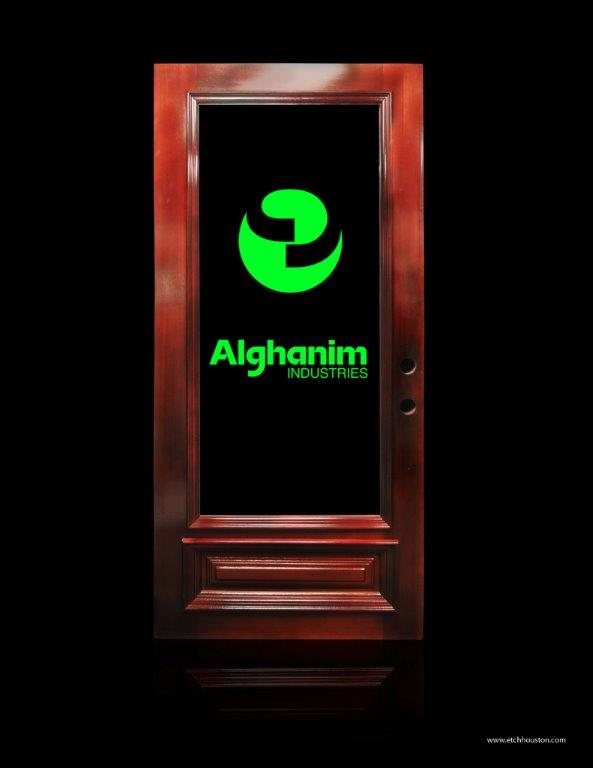 A door glass panel carved with a company mark and name, lit bright green from within.