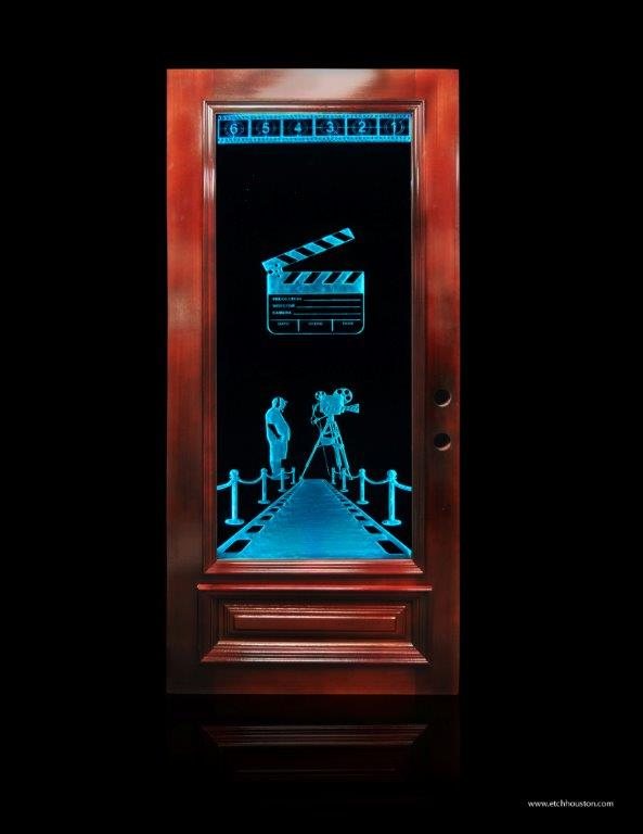 A door glass panel carved with a film camera, a clapperboard and a strip of film, lit blue from within.