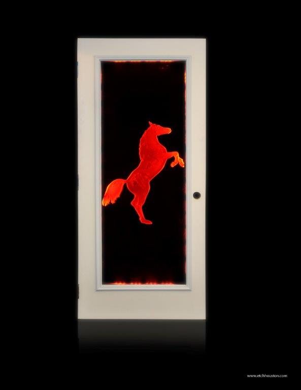 A door glass panel carved with a rearing horse, lit red from within.