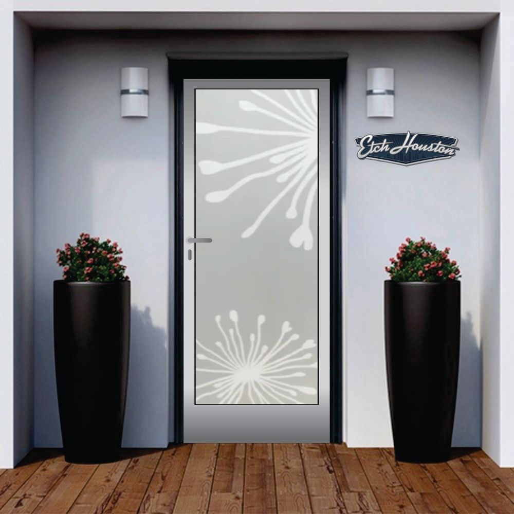 An entrance door with a decorative glass panel carrying two dandelion seed heads, between two tall black planters.