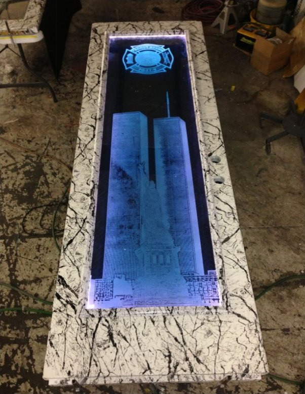 A narrow carved glass panel set flush into a stone countertop and lit blue from beneath.