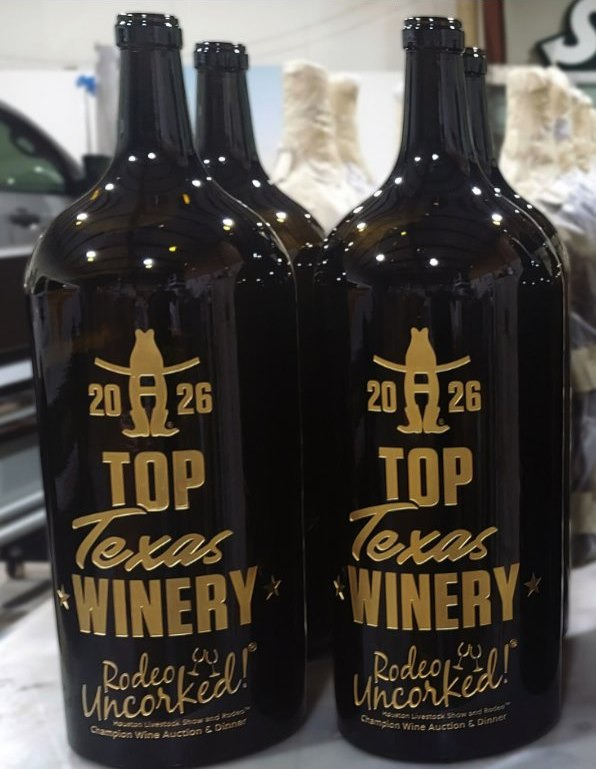 Two large black bottles etched in gold with a Top Texas Winery award design.