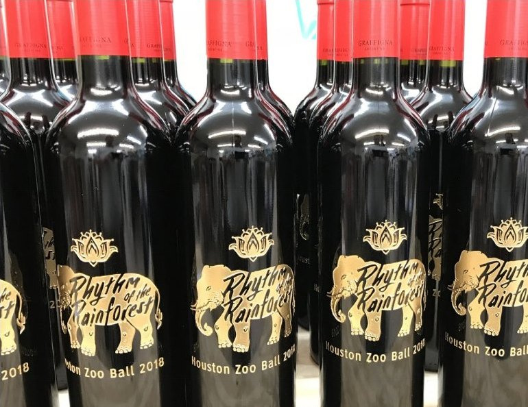 Rows of black bottles etched with an elephant crest and charity ball lettering.