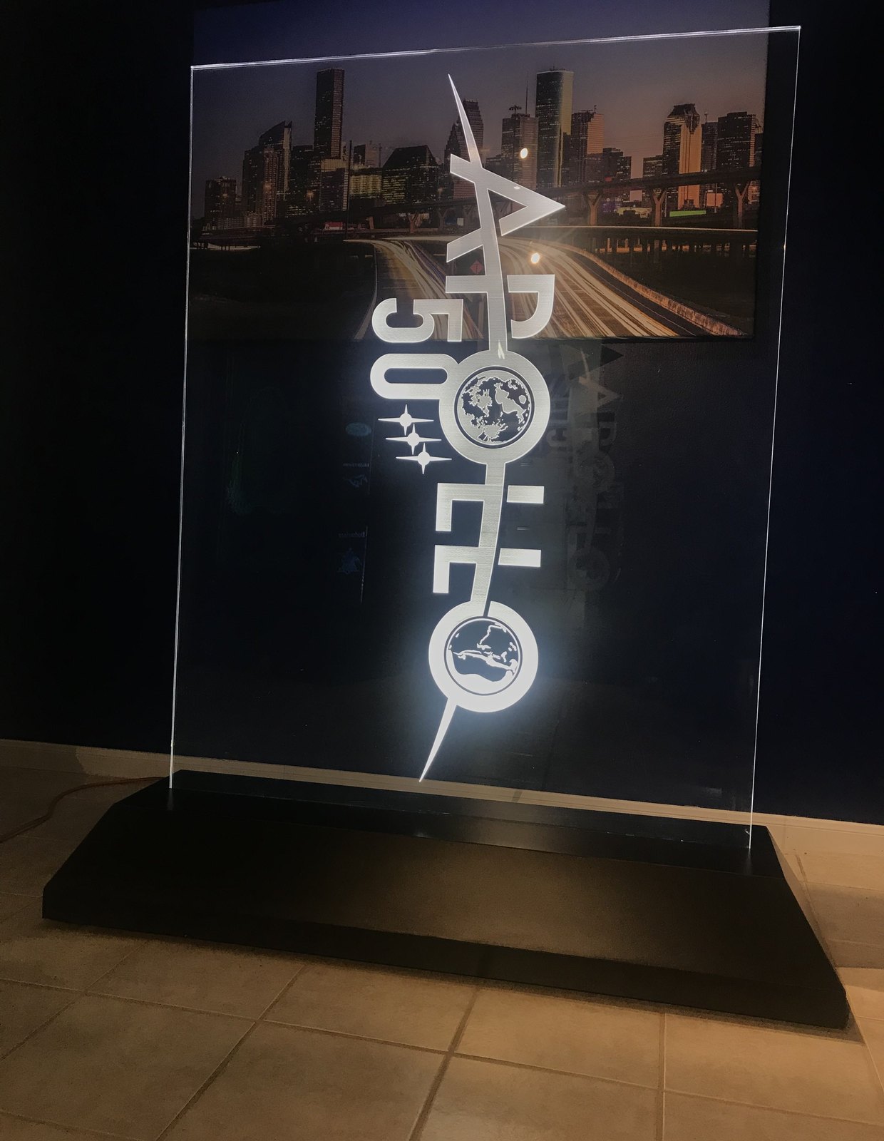 An illuminated etched glass display panel showing a space-programme anniversary graphic lit from the base.