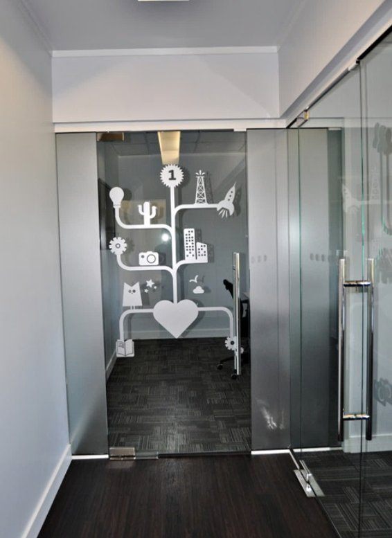 An office corridor lined with frosted privacy glass panels carrying a light decorative pattern.
