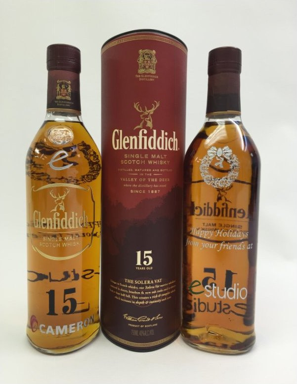 Two etched whisky bottles displayed beside their presentation tube in a retail setting.