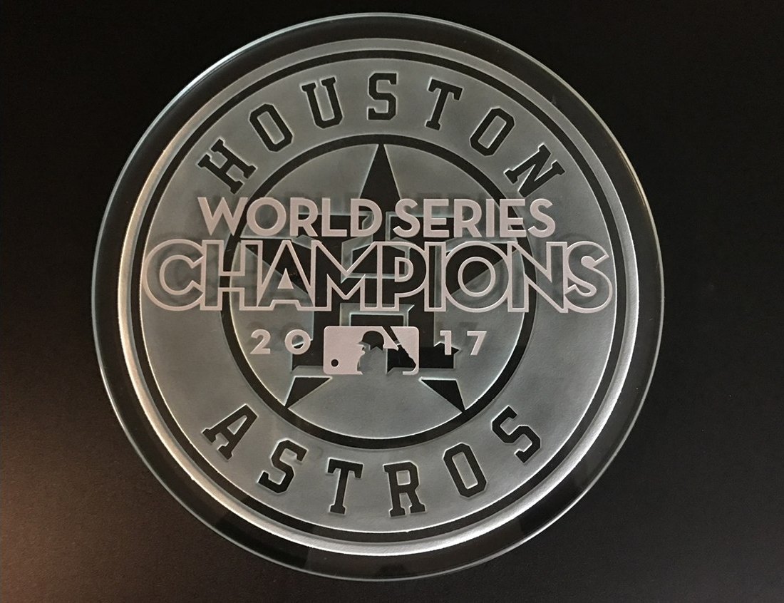 A deeply carved circular glass disc reading Houston Astros World Series Champions 2017, lit against a dark background.
