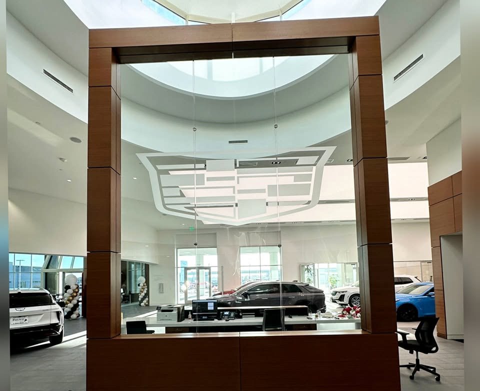 Finished showroom glass carrying a large frosted car marque crest, mounted above a timber reception desk.