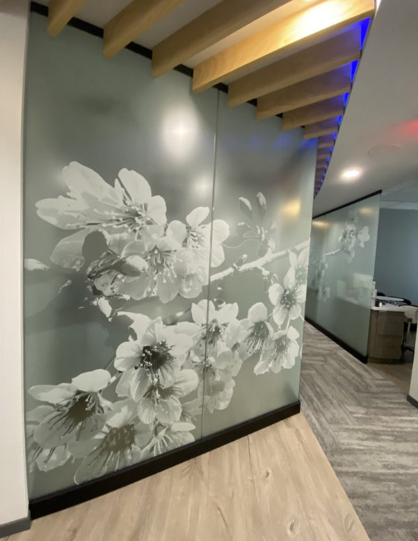 A frosted glass partition carved with a large flowering branch design in an office interior.