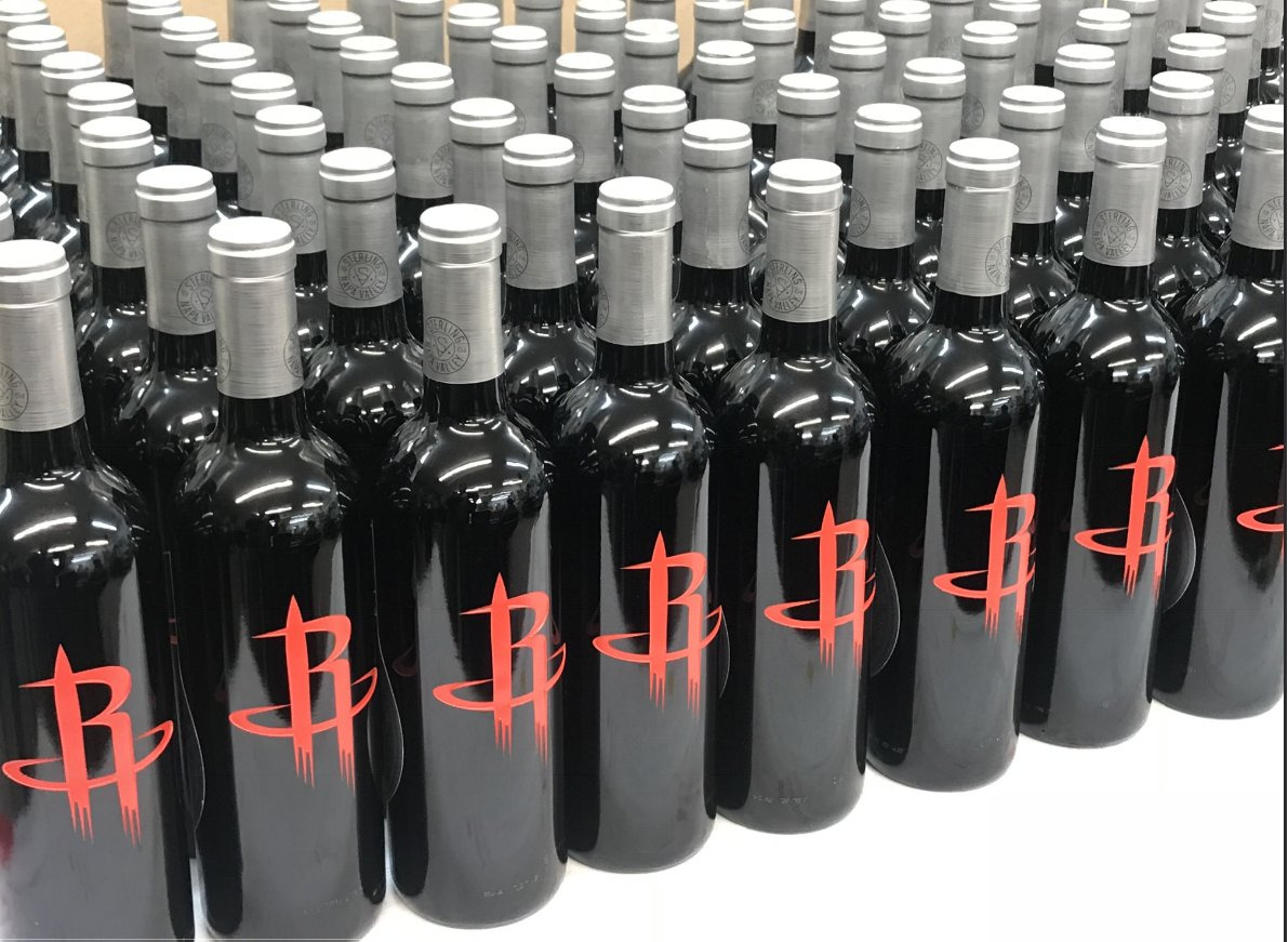 Rows of black bottles etched with a red Rockets mark, lined up across a table.