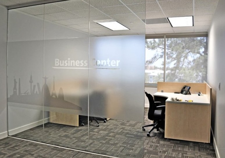 A glass-walled office suite with a frosted band and etched city skyline across the glass.