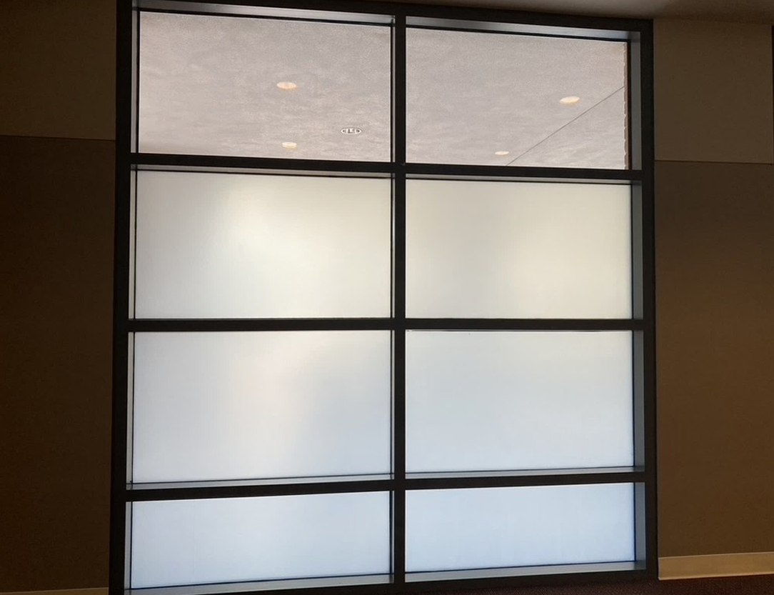 A framed grid of switchable glass panels in the frosted state, seen close up in an office.