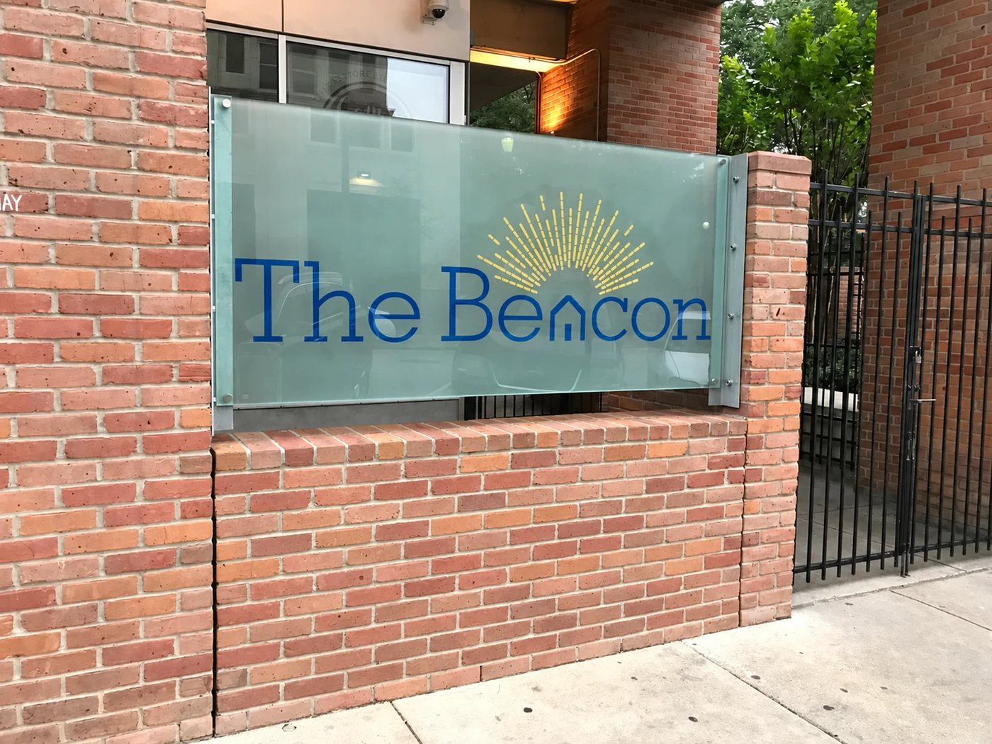 A storefront window with applied glass graphics reading The Beacon beside a brick facade.
