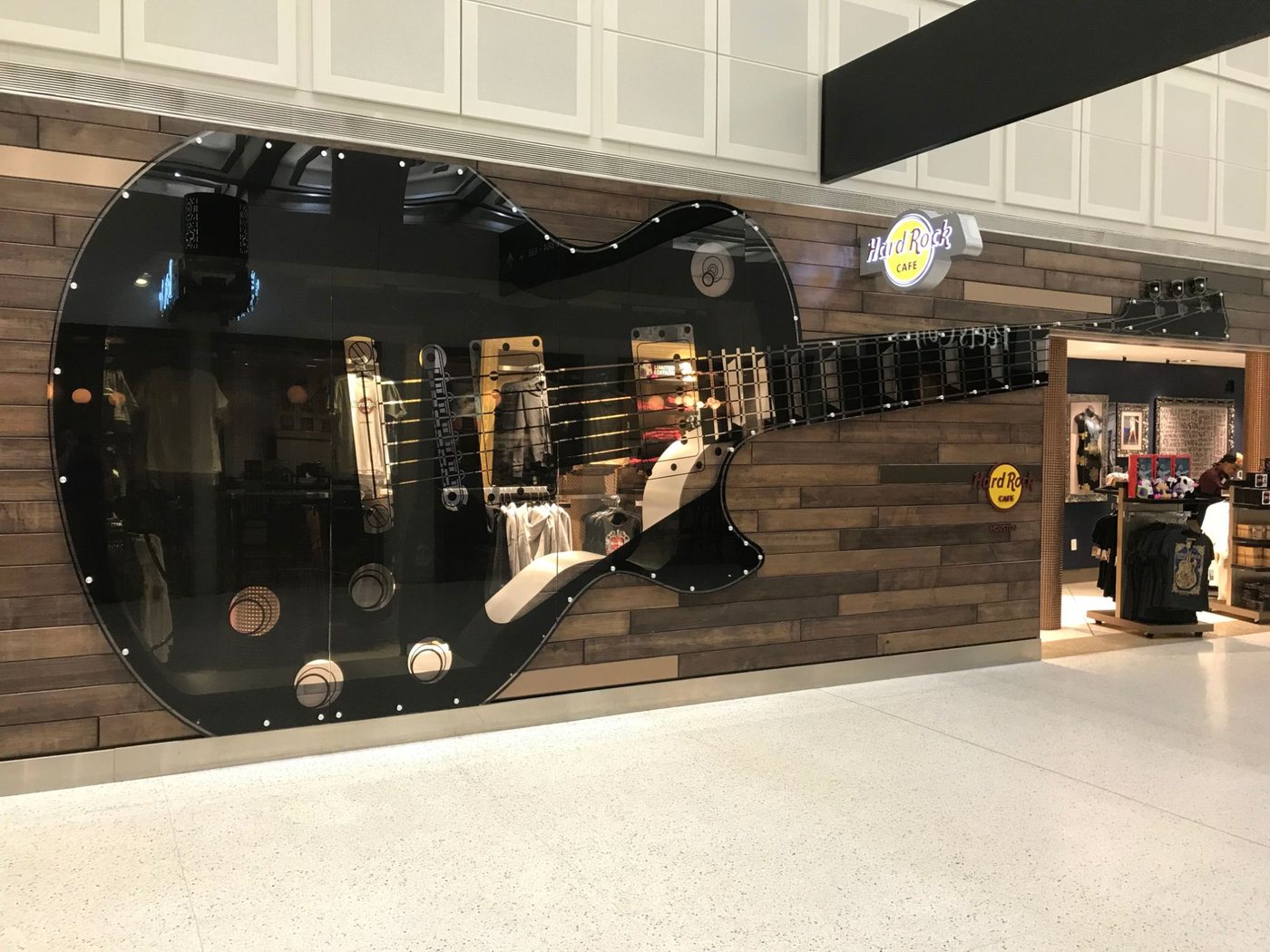 A shopfront glazed as an oversized black guitar, with the strings, frets and hardware picked out across the glass.