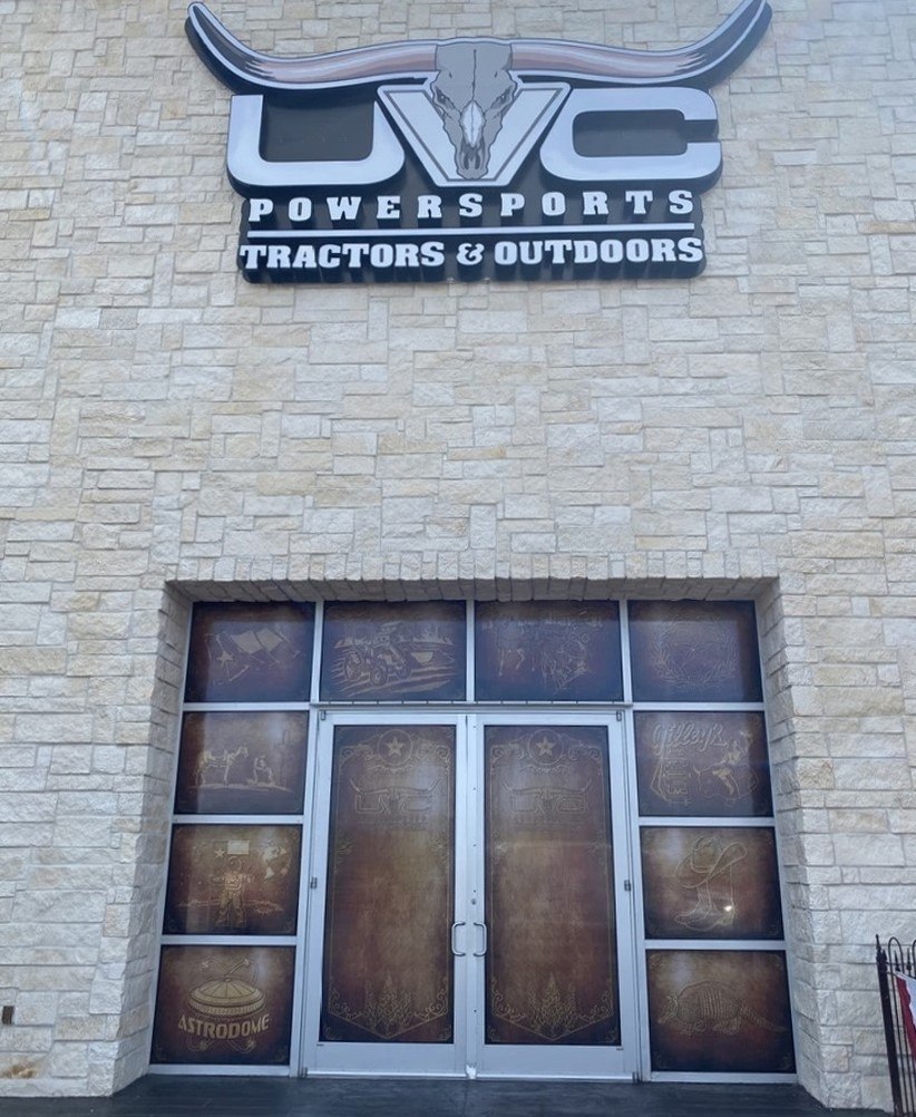 A retail storefront entrance with etched and printed glass graphics carrying the business name.
